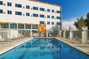 Una piscina al aire libre, sombrillas, sillones reclinables de piscina
