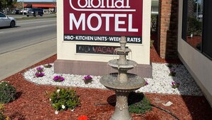 A Colonial Motel sign with a fountain and flower beds in front. - Colonial Motel (Santa Maria)