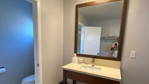 A bathroom with a wooden vanity, a mirror, and a toilet. - Colonial Motel (Santa Maria)