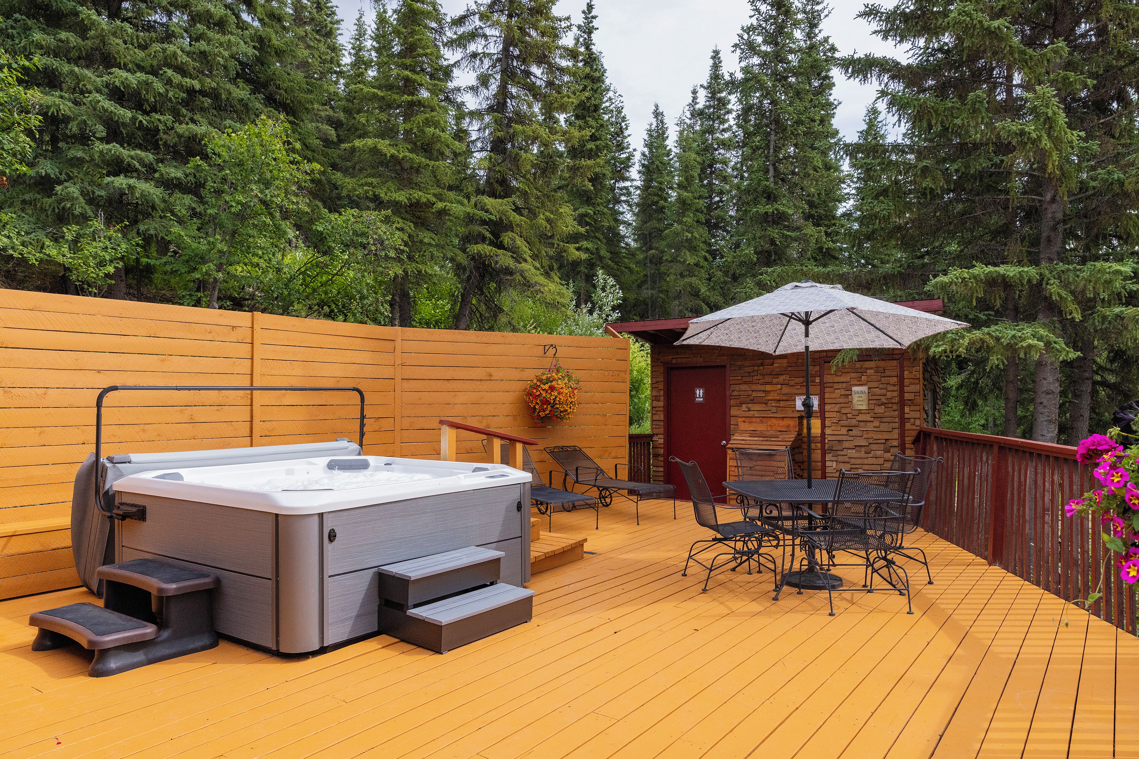 A wooden deck with a hot tub, outdoor seating, and a covered area.
