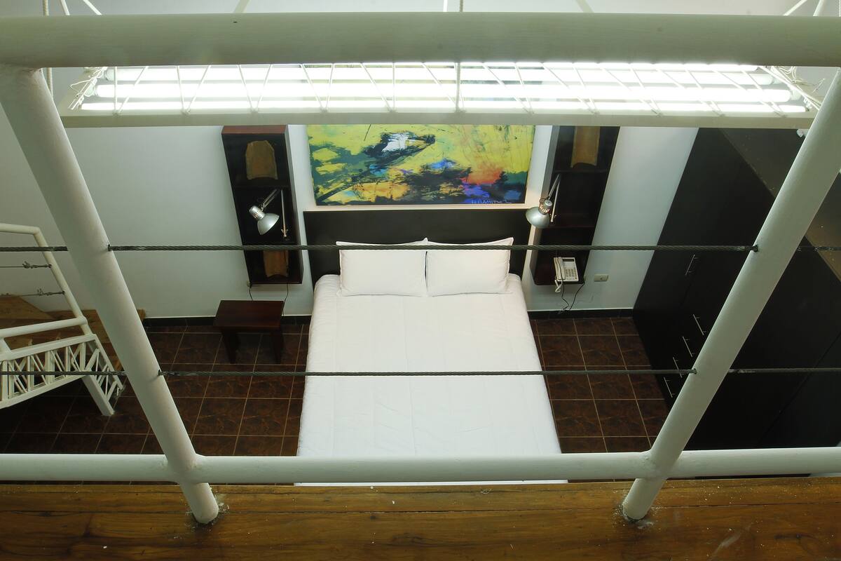 Una habitación de hotel con una cama, un cuadro en la pared y una ventana.