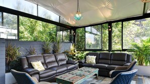 A sunlit room with two leather sofas, a coffee table, and blue chairs.