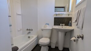 Un baño moderno con bañera, inodoro, lavabo y tocador.