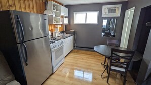Una cocina compacta con refrigerador, estufa, microondas y un comedor con mesa y sillas.