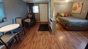 Una habitación pequeña con cama, una mesita, una silla y un sofá.