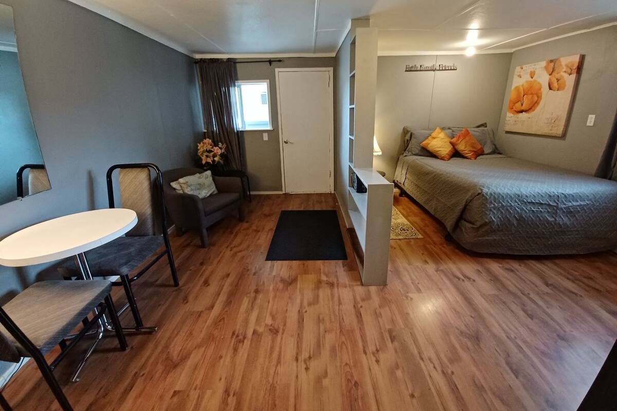 A compact room with a bed, a small table, a chair, and a sofa.