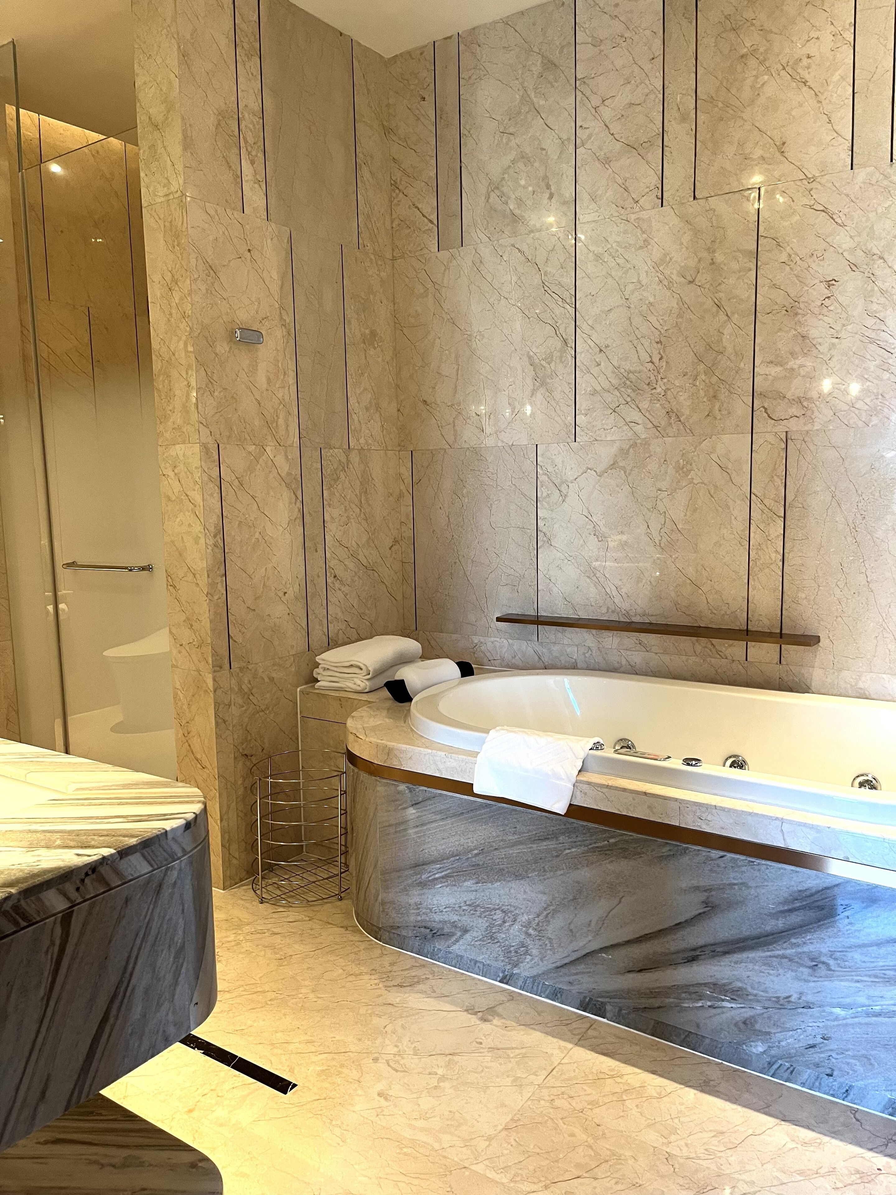 A modern bathroom with a marble vanity, a freestanding bathtub, and a glass shower enclosure.