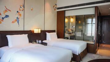 A hotel room with two beds, a large mirror, and a wall with a koi fish painting.