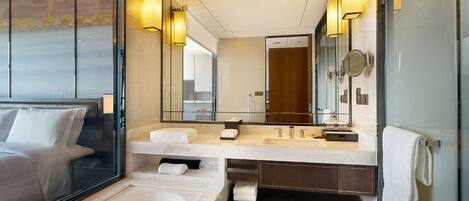 Un baño de hotel moderno con un espejo grande, lavamanos dobles, bañera y cabina de ducha de vidrio.