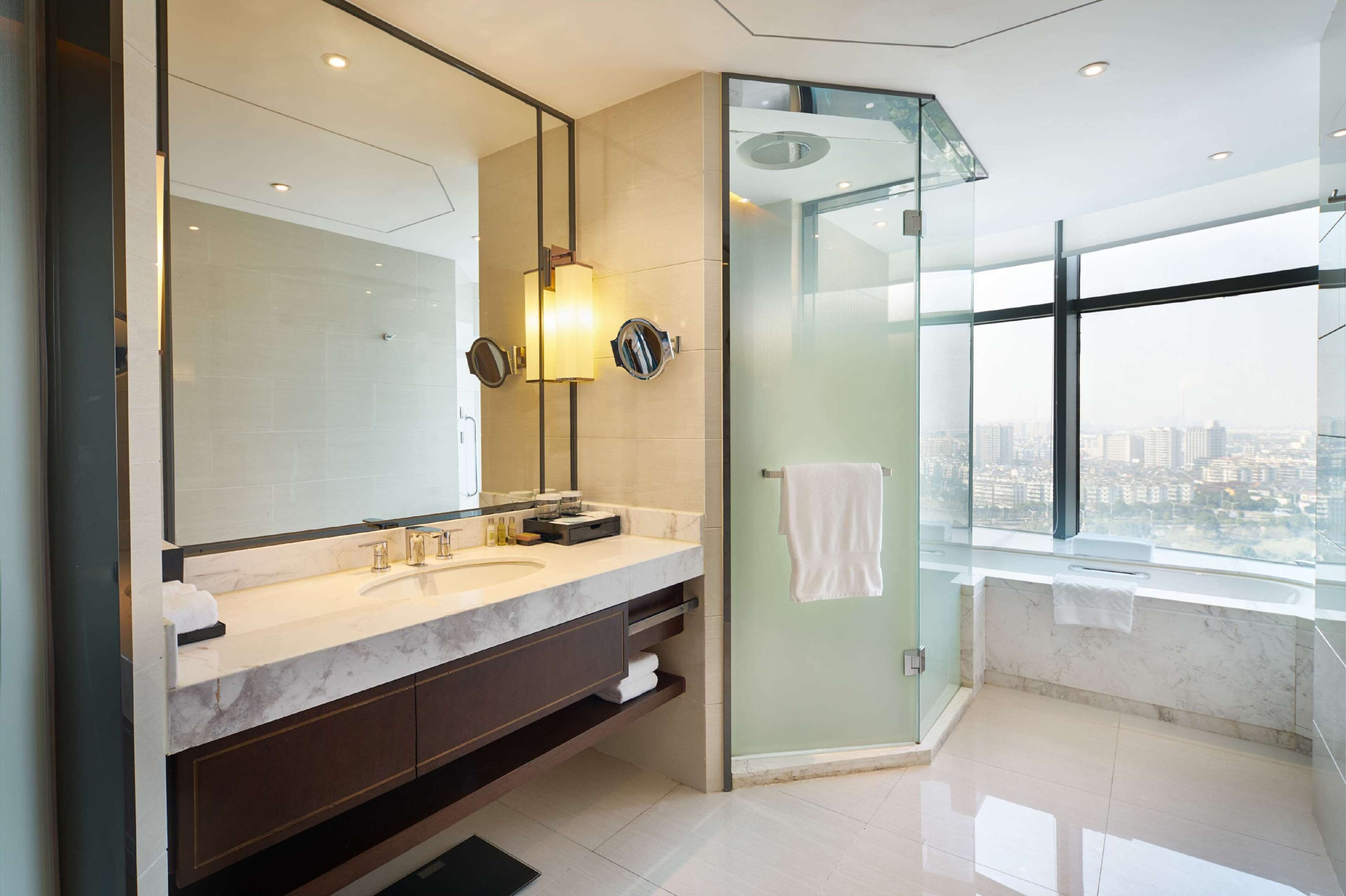 A modern bathroom with a large mirror, dual sinks, and a glass-enclosed shower.