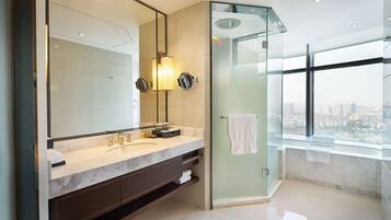 A modern bathroom with a large mirror, dual sinks, and a glass-enclosed shower.