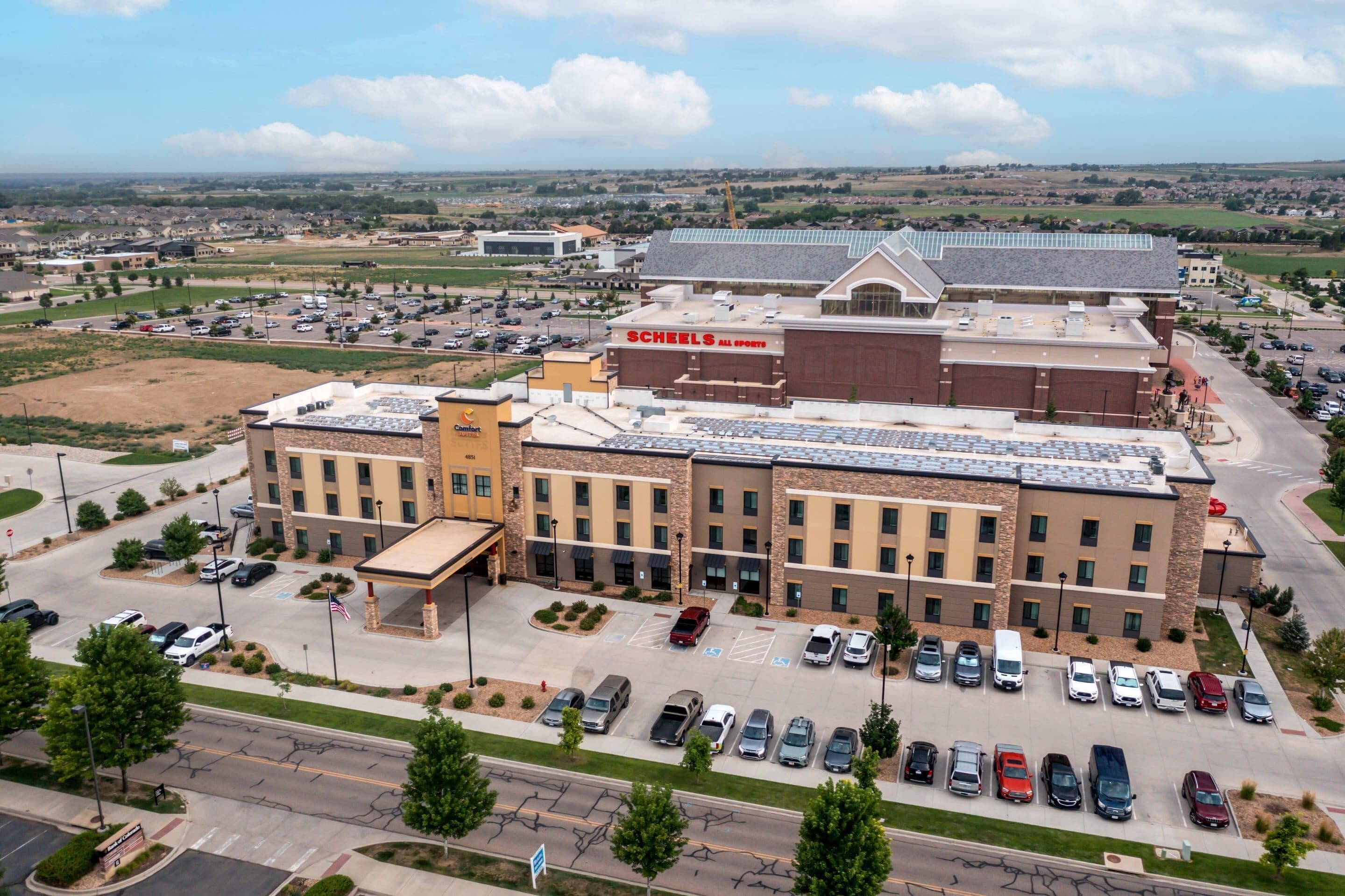 A multi-story hotel with a parking lot, a gas station, and a large building with 'Schenks All Sports' signage.