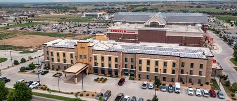 A multi-story hotel with a parking lot, a gas station, and a large building with 'Schenks All Sports' signage.