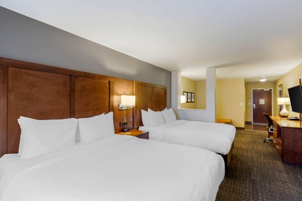 A hotel room with two beds, a desk, a chair, a lamp, and a television. - Comfort Suites Loveland (Loveland)