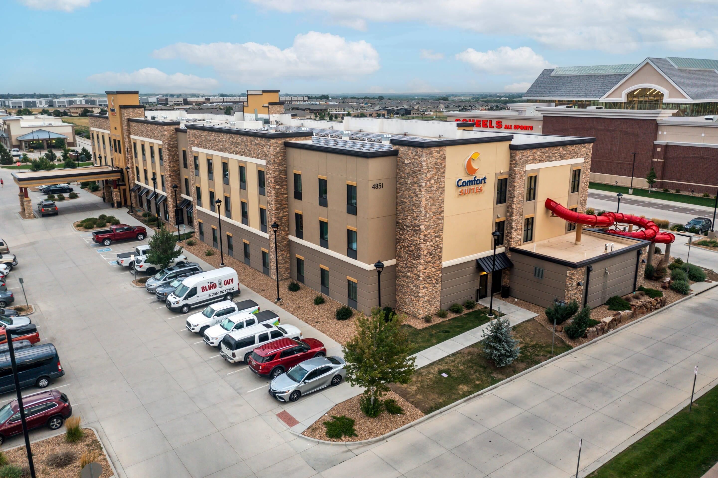 Un hôtel doté d’un parking, un bâtiment avec une enseigne « Comfort Suites », et un toboggan rouge.