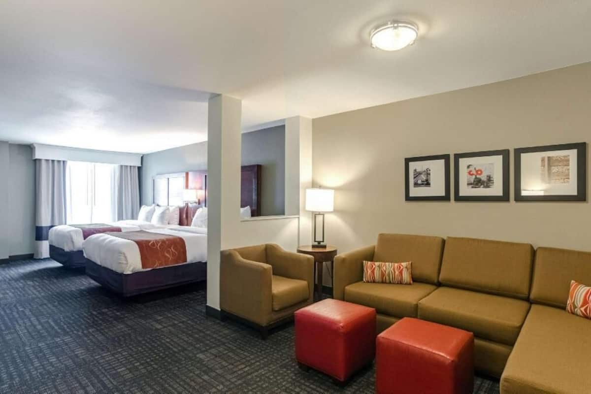 A hotel room with a bed, two armchairs, a sofa, a small table, and a lamp.