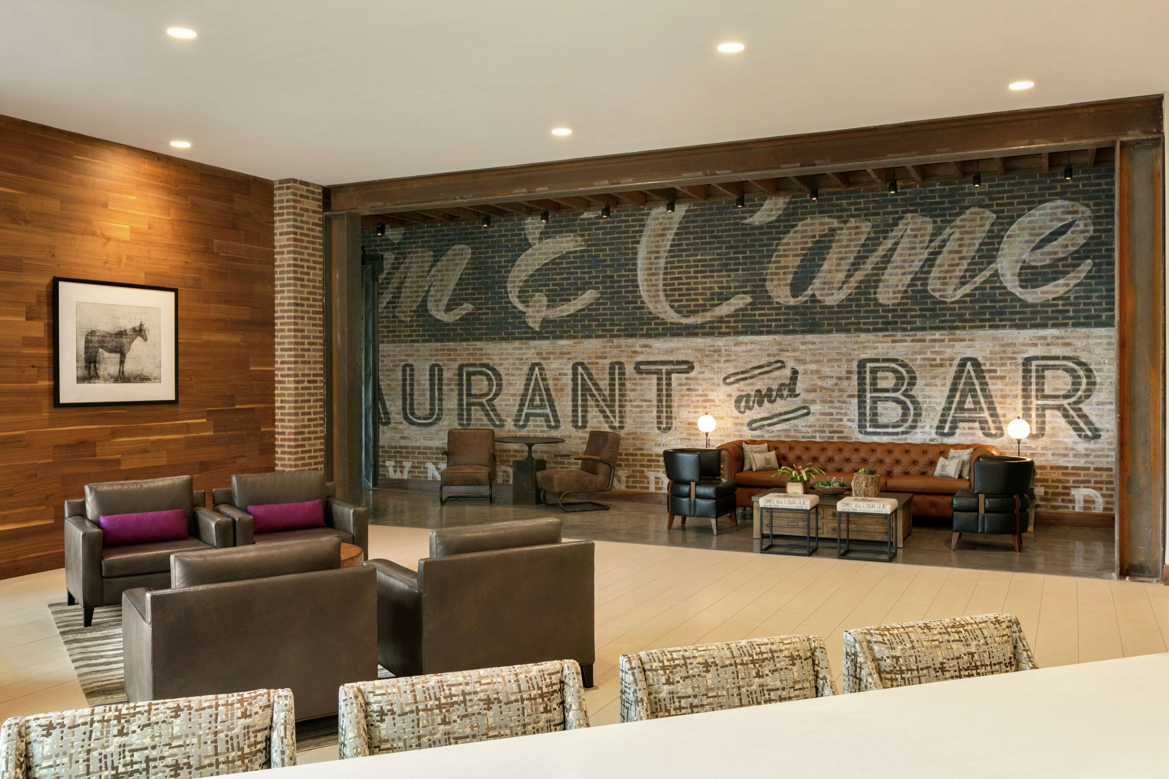 Un moderno bar con asientos de cuero y una amplia pared de ladrillo con el texto "McCameurant BAR".
