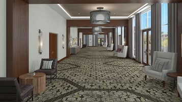 A hotel corridor with patterned carpet, modern lighting, and seating areas.
