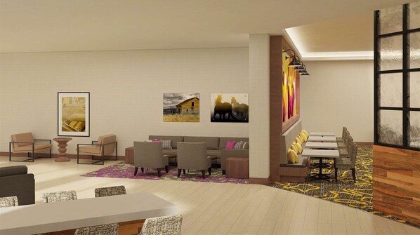 Un hall d’hôtel moderne avec un ensemble de canapés, des fauteuils, une table basse et des œuvres d’art accrochées aux murs.