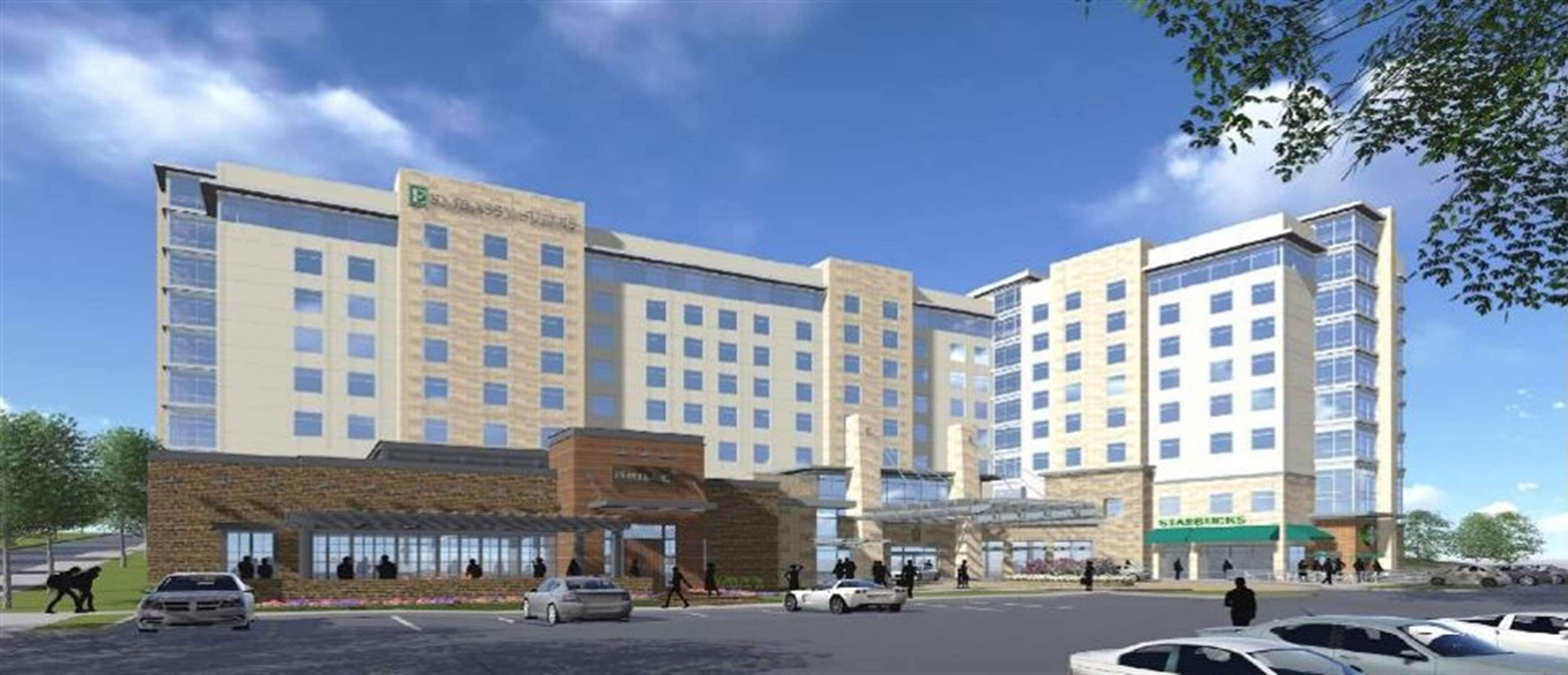 Een meerlaags hotel met een modern design, met een centrale ingang met een overdekt gedeelte en een Starbucks op de begane grond.