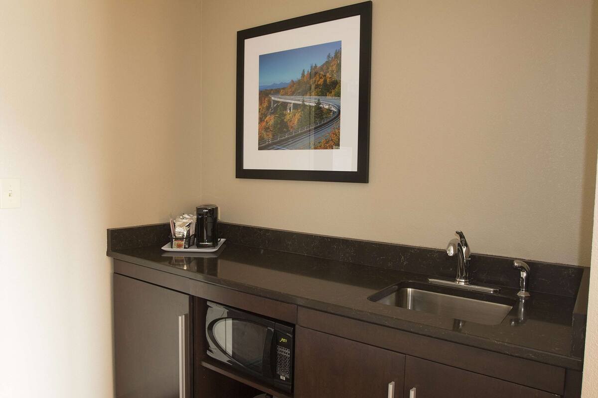 A kitchenette with a microwave, coffee maker, and sink.