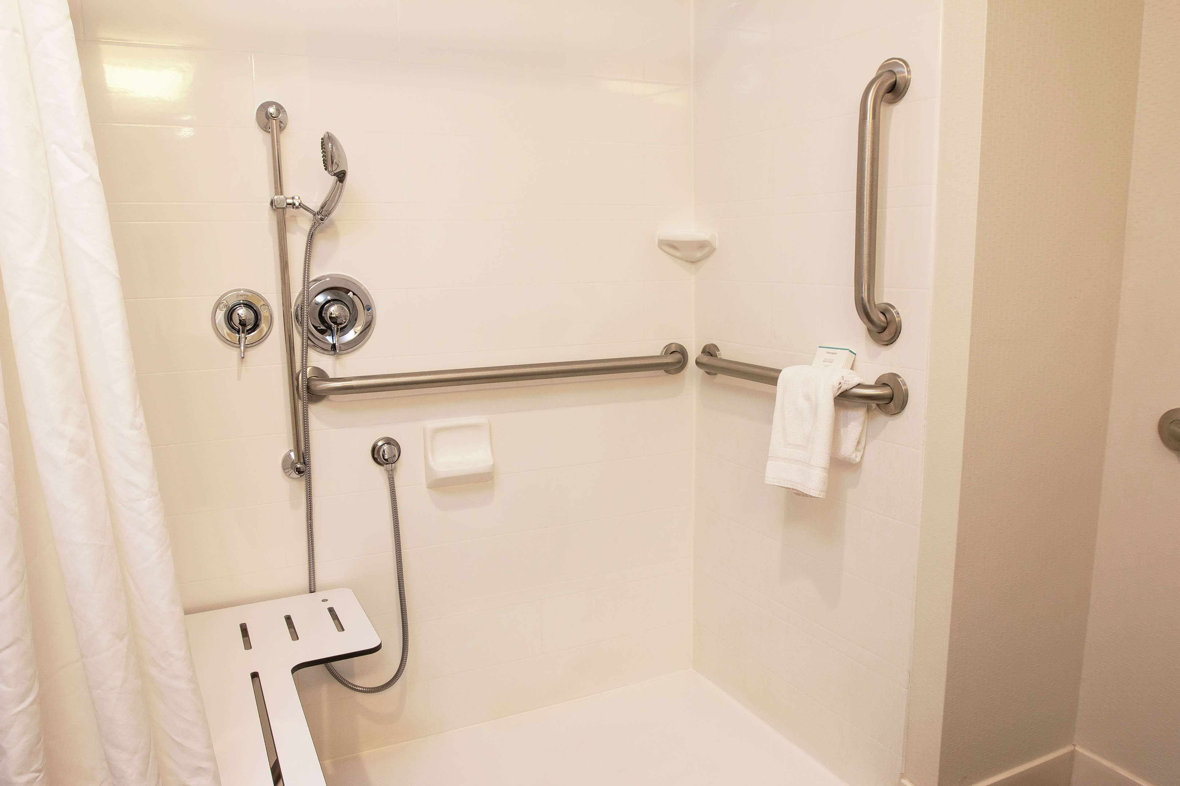 A bathroom with a walk-in shower, grab bars, a towel rack, and a soap dish.