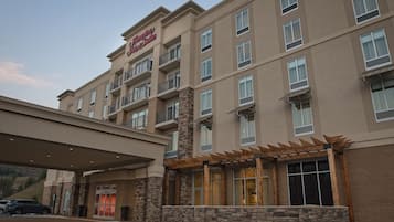 Een Hampton Inn hotel met een modern design, met meerdere balkons en een overdekte ingang.