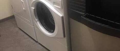 Lavadora y secadora de carga frontal con panel de control y símbolo de mano que indica función de seguridad infantil.
