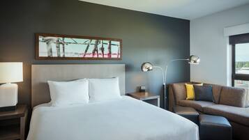 Ein Hotelzimmer mit einem großen Bett, einer Couch, einem Nachttisch mit Lampe und einem Gemälde an der Wand.