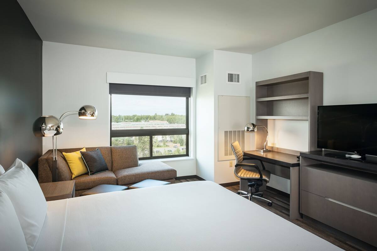 Una camera d'albergo moderna con un letto grande, una scrivania, un televisore e un divano.