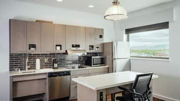 A modern kitchen with a dishwasher, microwave, and a large window offering a view of the outdoors.