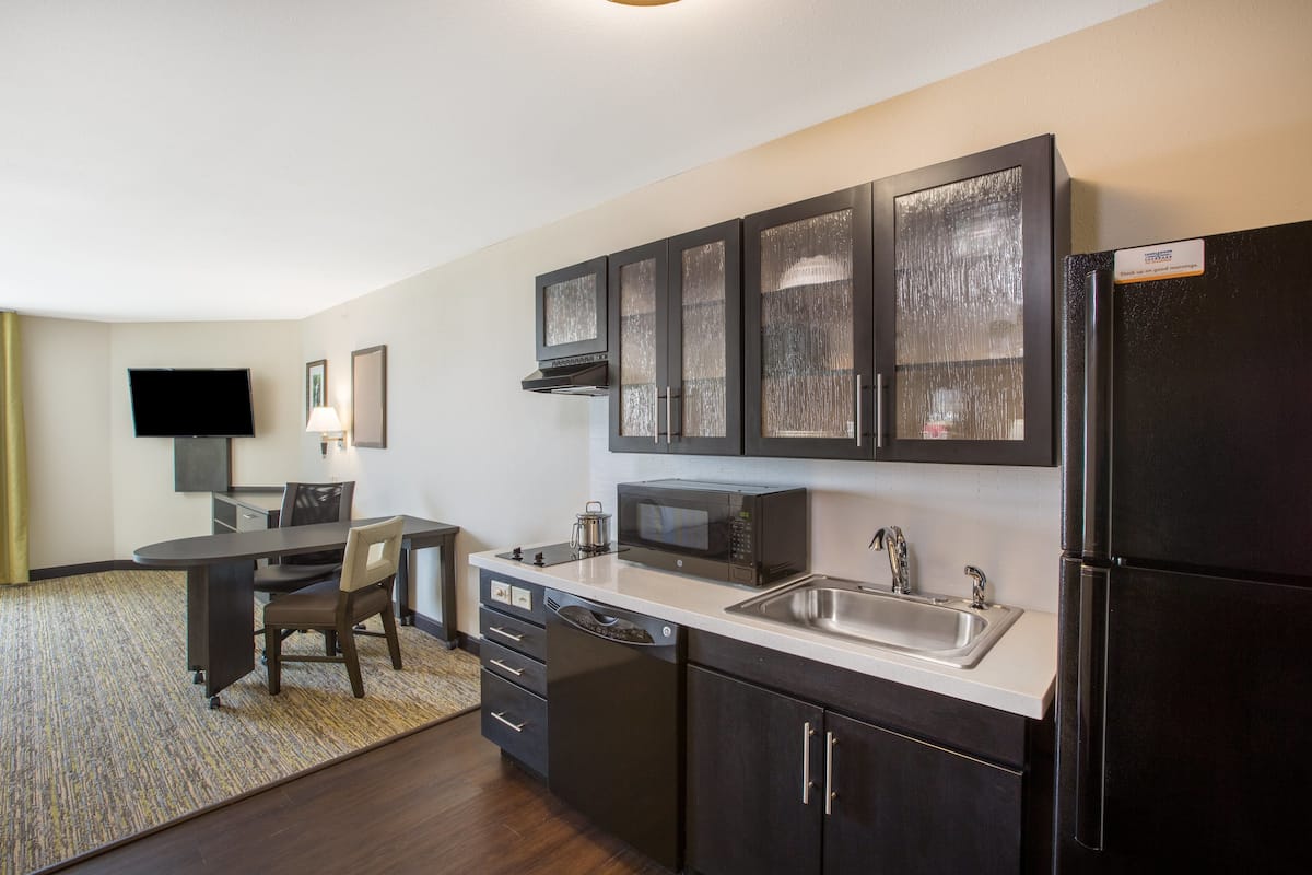 A modern kitchen with a flat-screen TV, a microwave, a refrigerator, and a sink.
