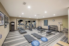 Ein Fitnessstudio mit Laufbändern, Crosstrainern und Kurzhanteln.