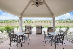 Eine Außenpatio mit Grill, Tischen und Stühlen.