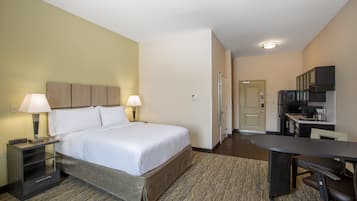 Ein Hotelzimmer mit Bett, Nachttischen, Schreibtisch und einer Küchenzeile.