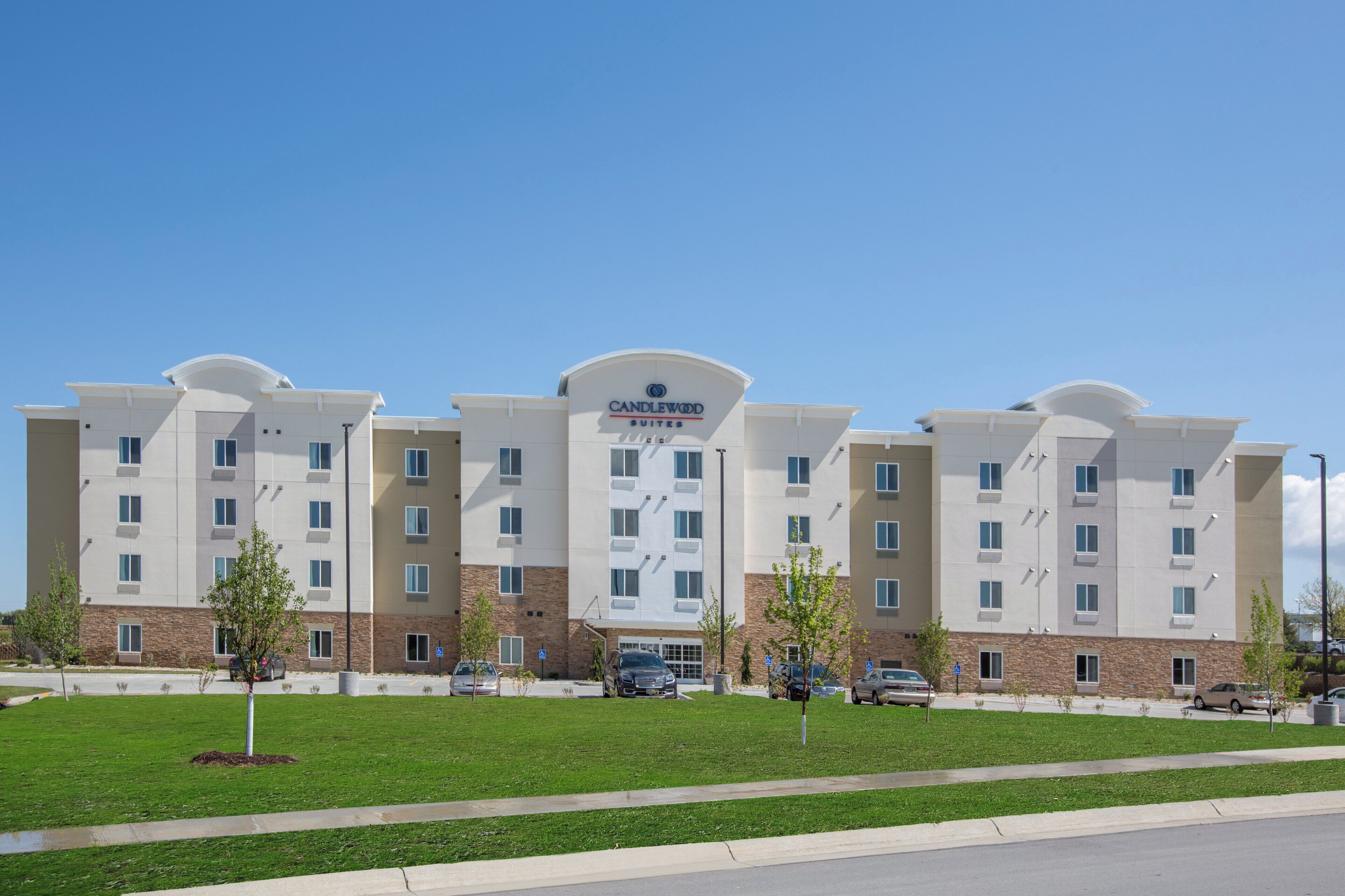 A multi-story hotel with a flat facade, a central entrance, and a parking lot in front.