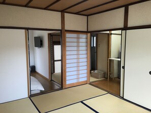 Een traditionele Japanse kamer met tatami vloerbedekking, schuifdeuren en een televisie.