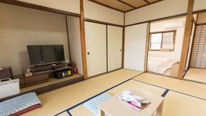 A traditional Japanese room with tatami flooring, a television, a small table, and sliding doors. - Kyo no Yado Jorinji (Kyoto)