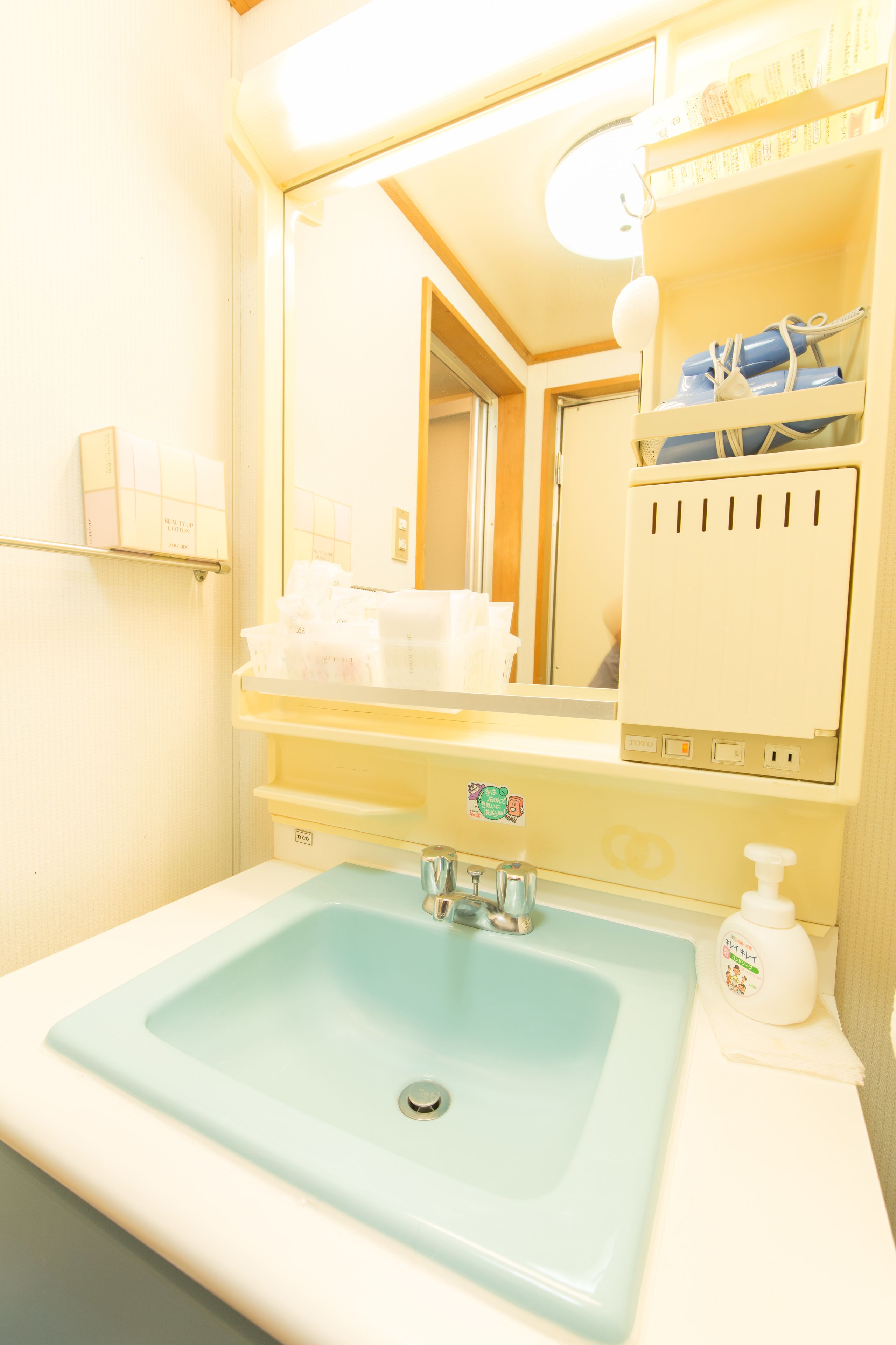 Un baño con un lavamanos azul claro, un espejo y un estante con artículos de aseo.