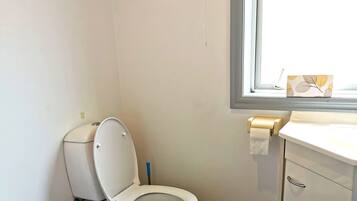 Un baño con inodoro, lavabo, bidé y ventana.