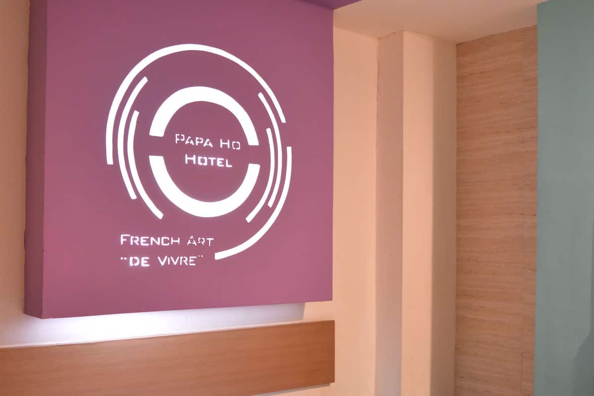 A hotel room with a bed, pillows, and a wall with a logo and text.
