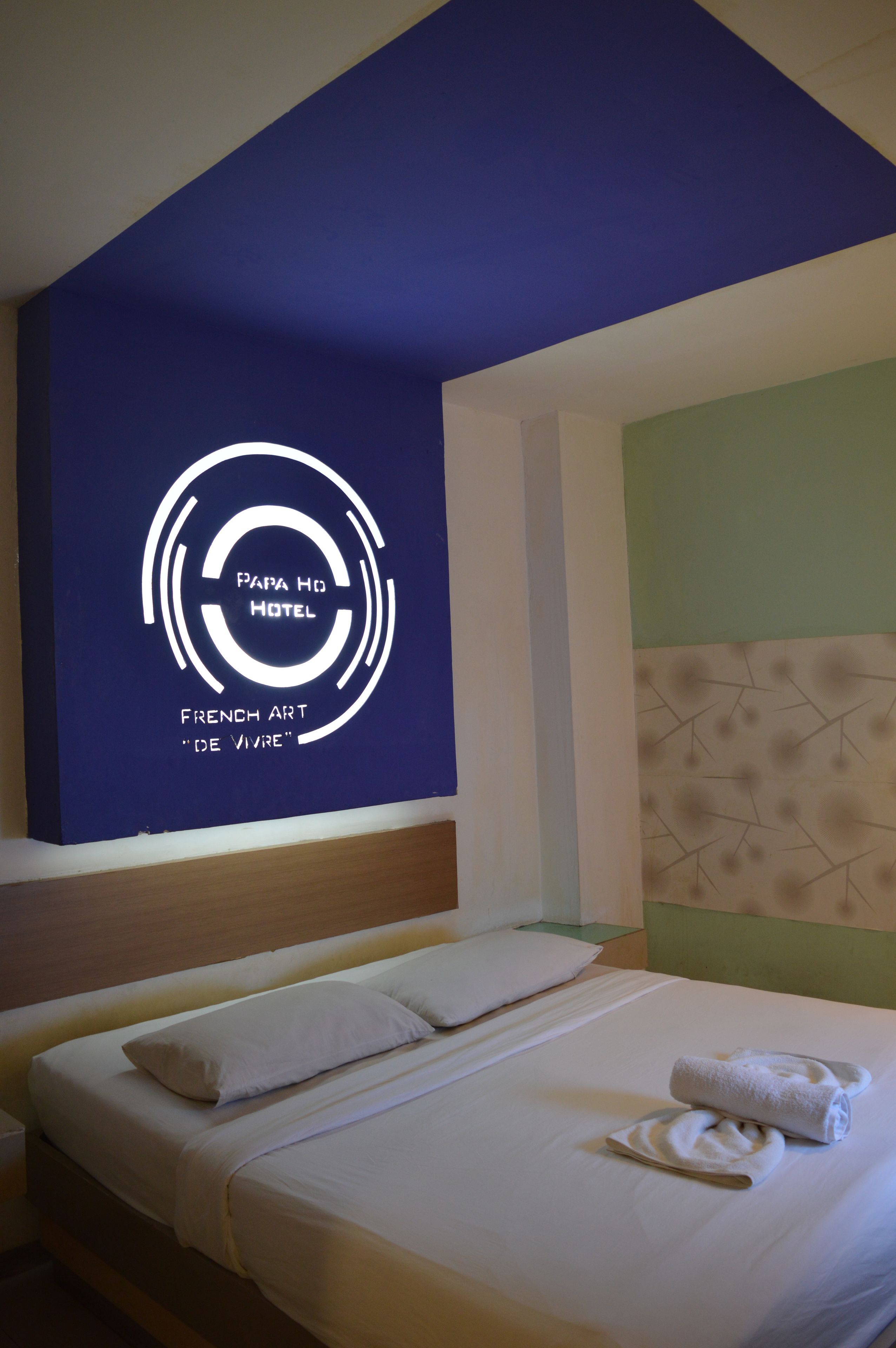 Una camera d'albergo con un letto, cuscini e una parete con un logo e del testo.