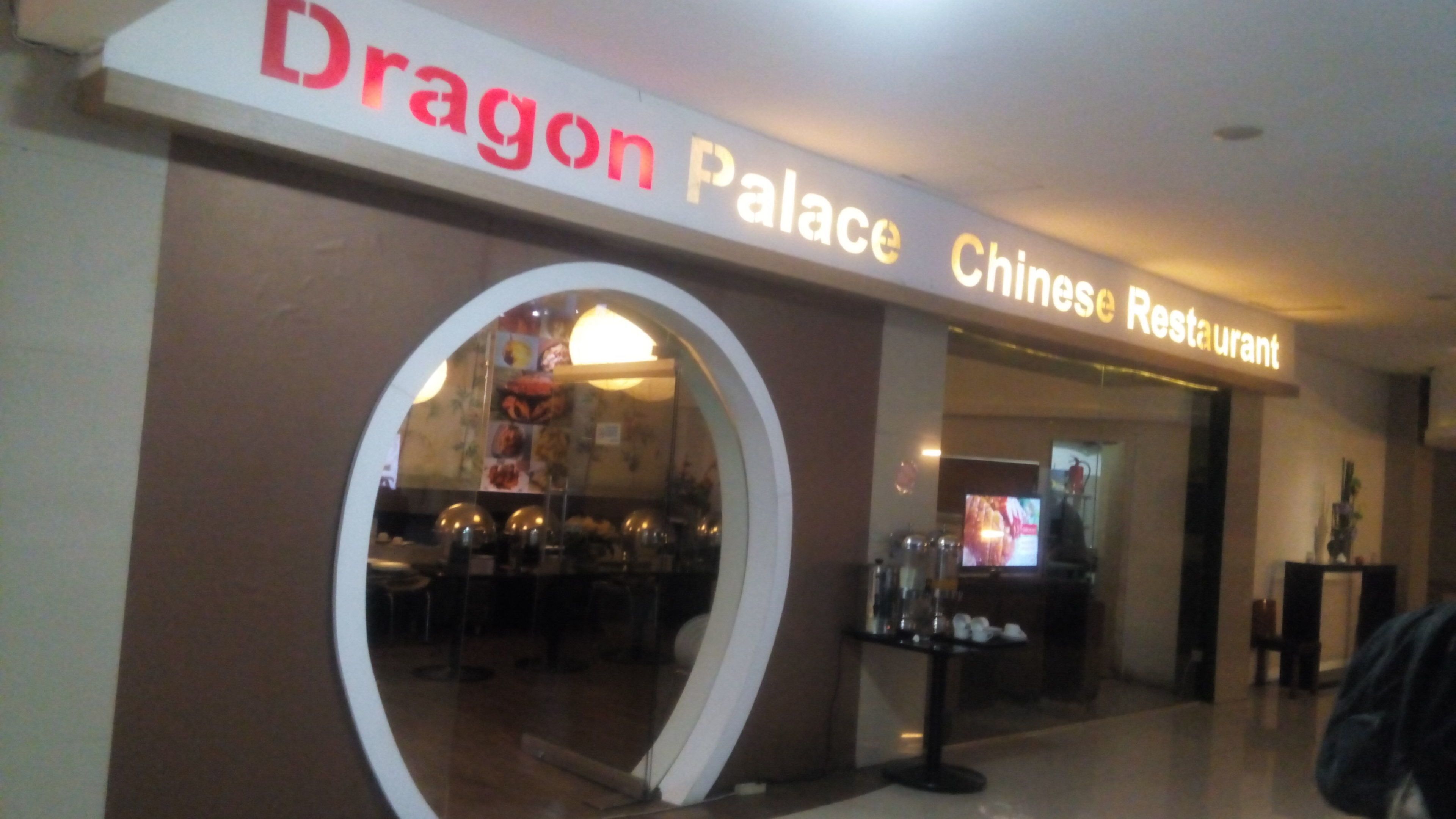 Fachada del Restaurante Chino Dragon Palace, con un ventanal circular y un letrero sobre la entrada.