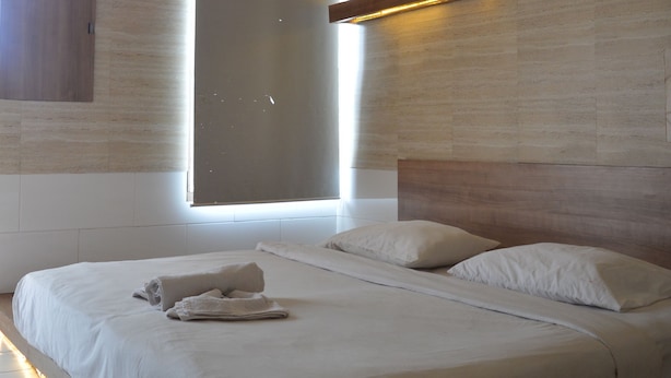 Un dormitorio moderno con una cama grande, cabecero integrado e iluminación ambiental.
