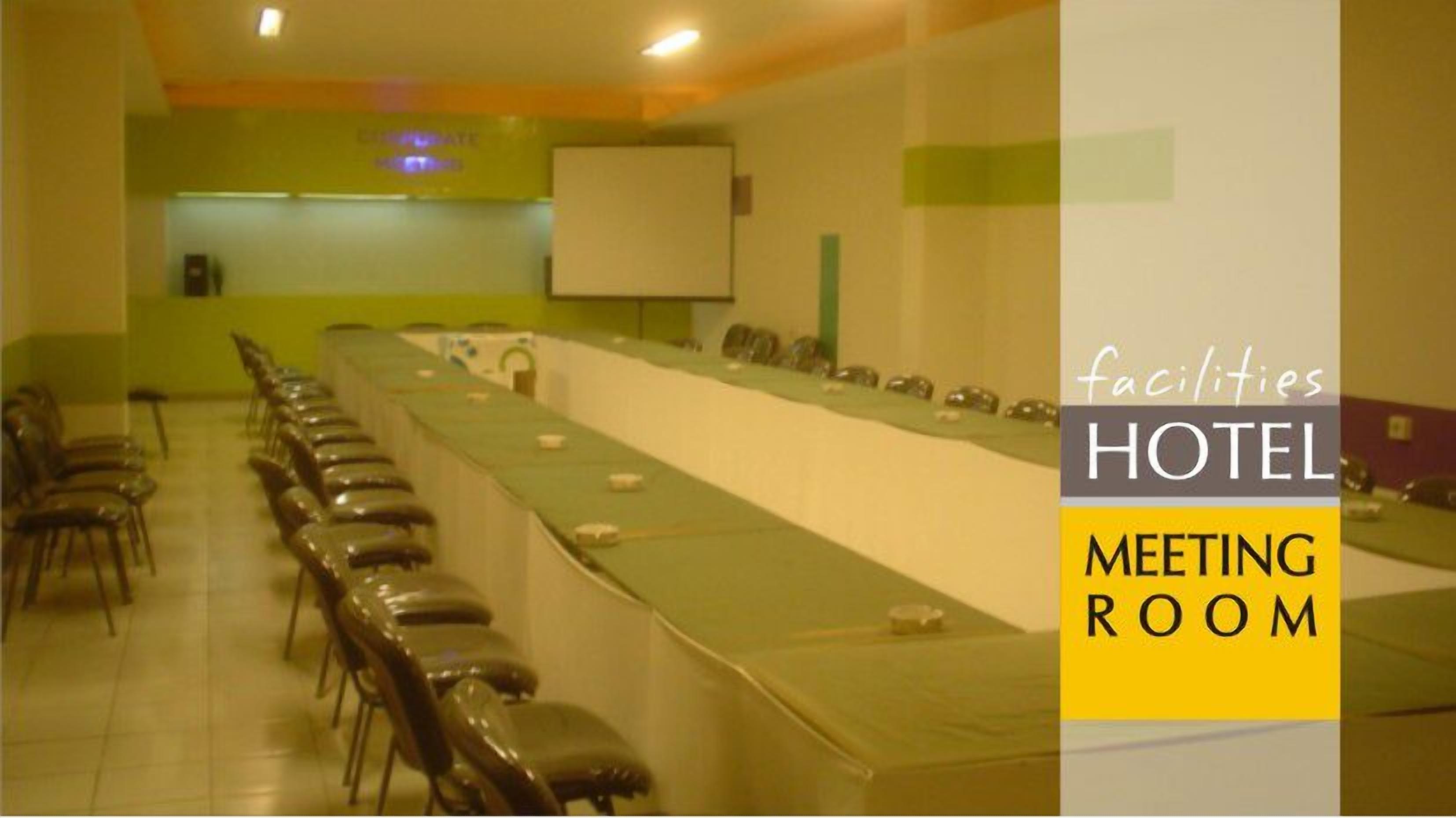 Ein Hotelkonferenzraum mit einem langen Tisch, Stühlen und einer Projektionsleinwand.