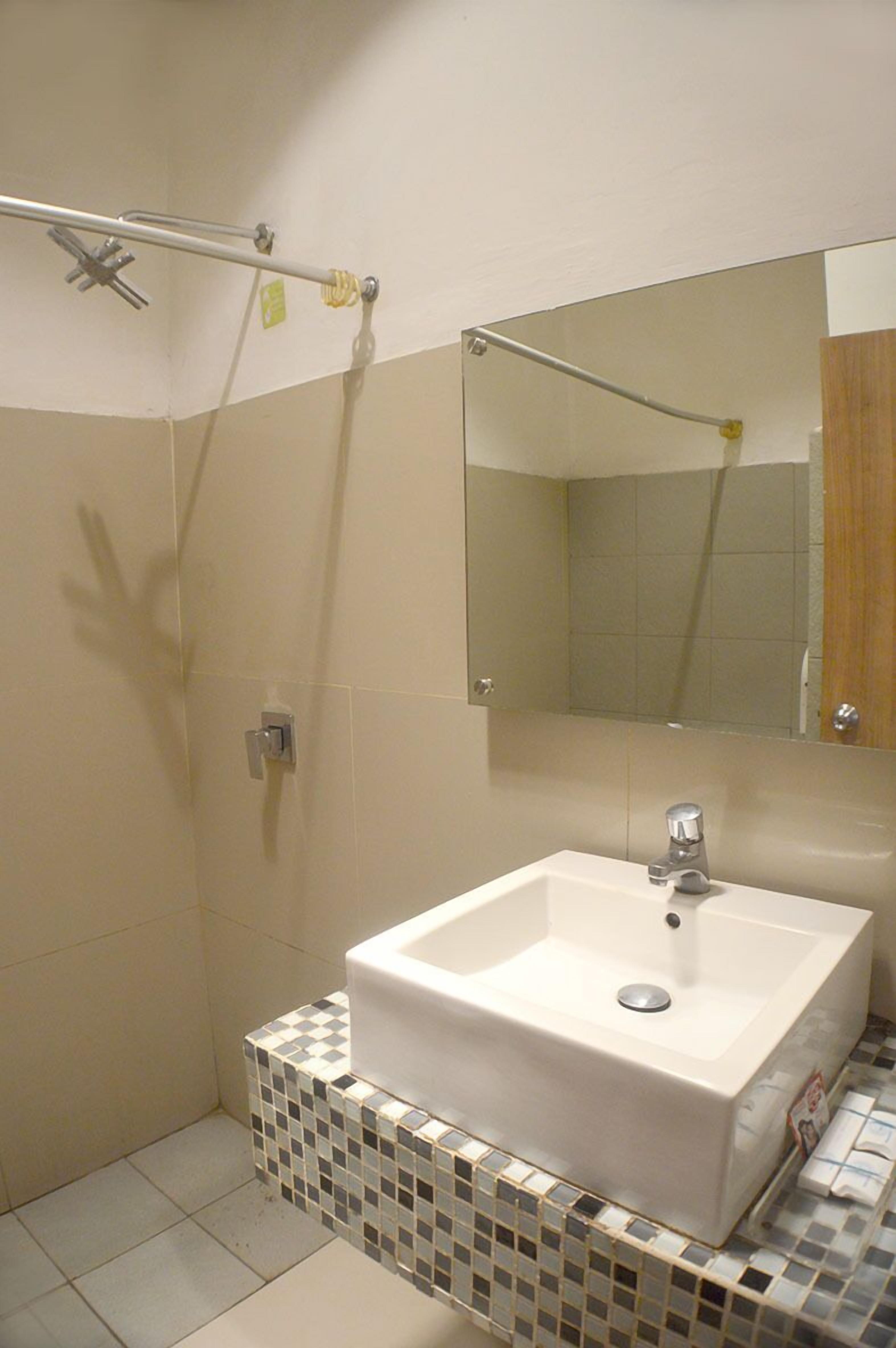 Ein Badezimmer mit einem weißen Waschbecken, einem Spiegel und einer Duschkabine.