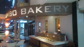 Una panadería con un letrero que dice "BUMBO BAKERY" y un mostrador con botes de productos horneados.