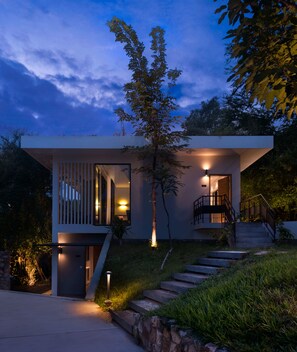 Ein modernes Haus mit einer Treppe, die zu einem Balkon führt, umgeben von viel Grün.