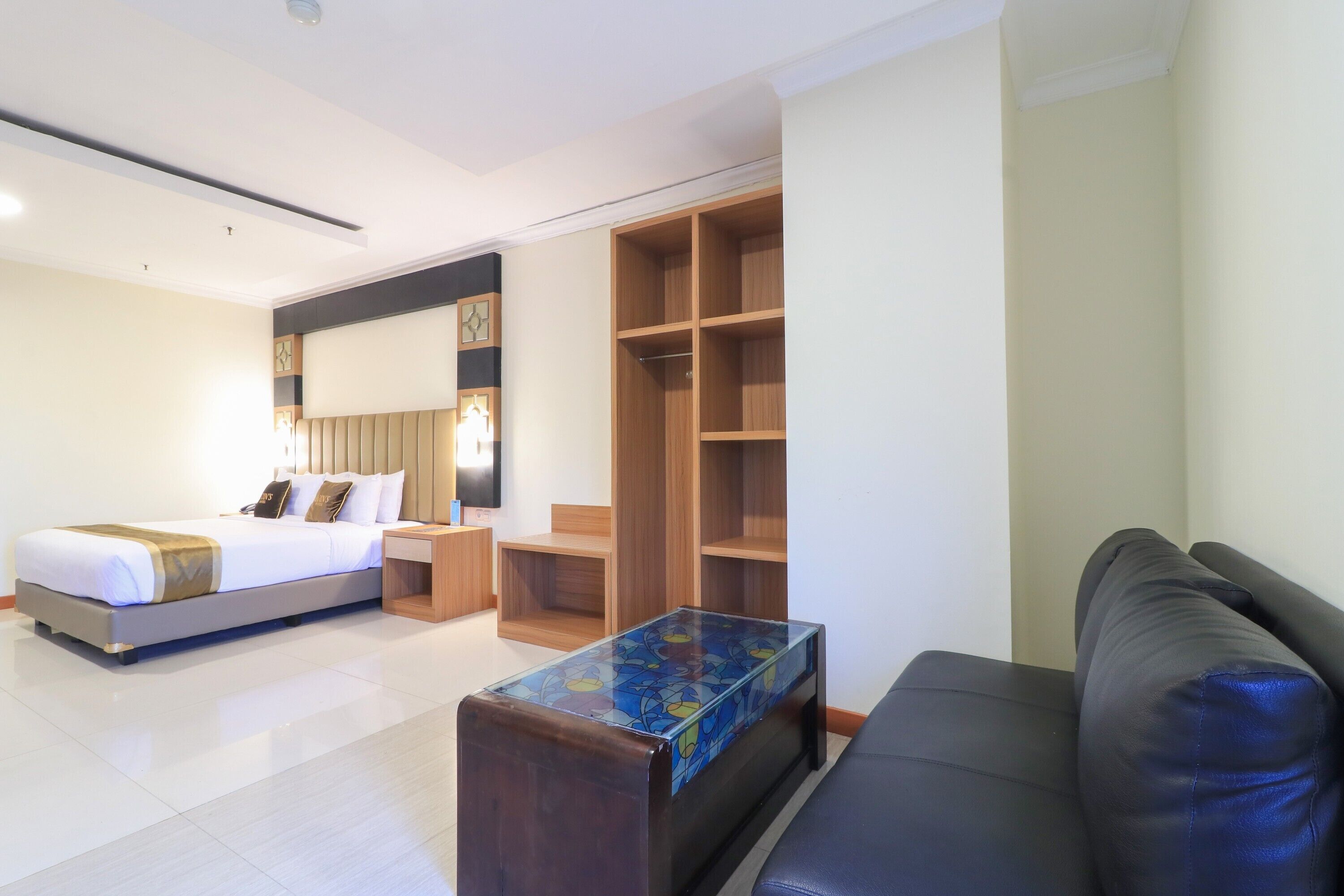 A hotel room with a bed, a desk, a wardrobe, and a sofa.