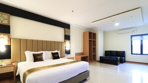 Una habitación de hotel moderna con una cama grande, televisión, zona de estar y armario.
